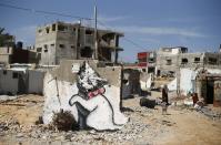 A mural of a playful-looking kitten, presumably painted by British street artist Banksy, is seen on the remains of a house that witnesses said was destroyed by Israeli shelling during a 50-day war last summer, in Biet Hanoun town in the northern Gaza Strip February 26, 2015. The anonymous but eminent British street artist known as Banksy has posted a mini-documentary on his banksy.co.uk site showing squalid conditions in Gaza six months after the end of the war between the enclave's Islamist Hamas rulers and Israel. REUTERS/Suhaib Salem (GAZA - Tags: POLITICS CIVIL UNREST SOCIETY TPX IMAGES OF THE DAY)