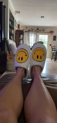 A pair of smiley face slippers with a foam sole and plush fabric to keep your feet happy