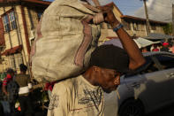 A market worker carries a sack of fruits at Stabroek Market in Georgetown, Guyana, Thursday, April 13, 2023. More than 40% of the population lived on less than $5.50 a day when oil production began in 2019. (AP Photo/Matias Delacroix)