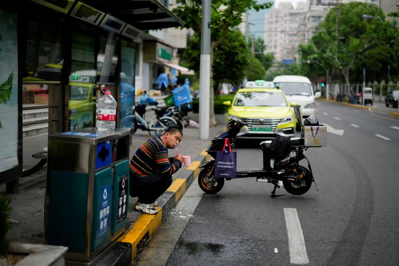 FILE PHOTO: A delivery worker brushes his teeth on a street in Shanghai