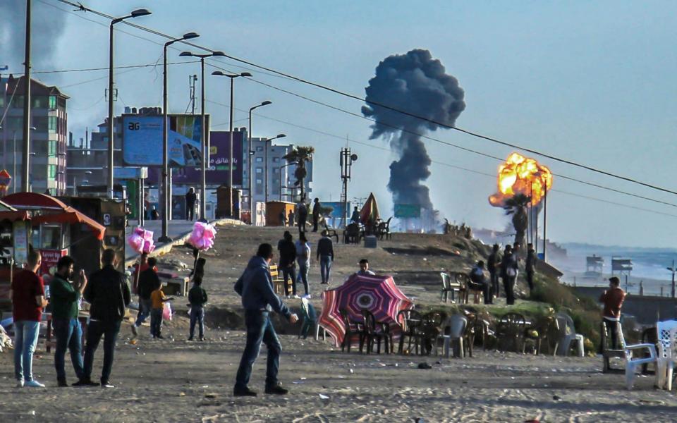 Palestinians gather on the beach in Gaza City as smoke and fire billow following airstrikes by Israel in response to rockets fired by Palestinian militants on May 4, 2019 - SAMI AL-SULTAN/AFP/Getty Images