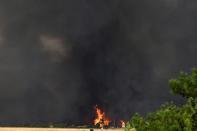 Flames burn near buildings outside an Air Base in Tatoi area, northern Athens, Greece, Tuesday, Aug. 3, 2021. Greece Tuesday grappled with the worst heatwave in decades that strained the national power supply and fueled wildfires near Athens and elsewhere in southern Greece. As the heat wave scorching the eastern Mediterranean intensified, temperatures reached 42 degrees Celsius (107.6 Fahrenheit) in parts of the Greek capital. (AP Photo/Michael Varaklas)