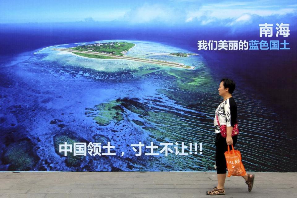 FILE - In this July 14, 2016 file photo, a woman walks past a billboard featuring an image of an island in South China Sea on display with Chinese words that read: "South China Sea, our beautiful motherland, we won't let go an inch" in Weifang in east China's Shandong province. A U.S. think tank says recent satellite images appear to show that China has installed anti-aircraft and anti-missile weapons on its man-made islands in the South China Sea. (Chinatopix via AP, File)