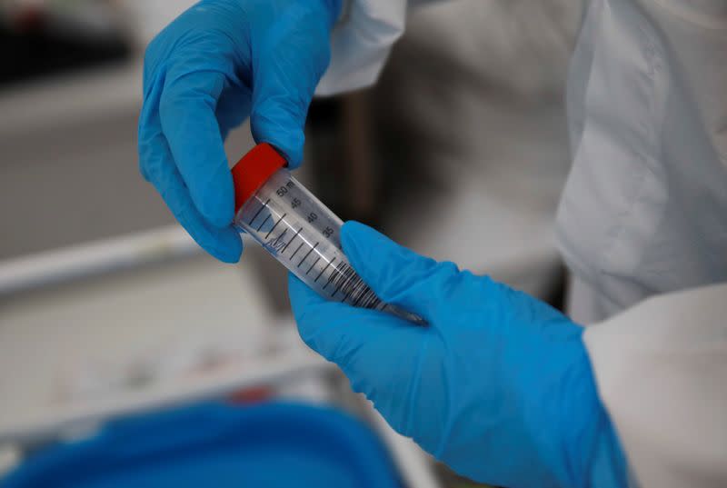 A woman wearing a protective coverall holds a test at a coronavirus disease (COVID-19) drive-thru testing centre in Warsaw