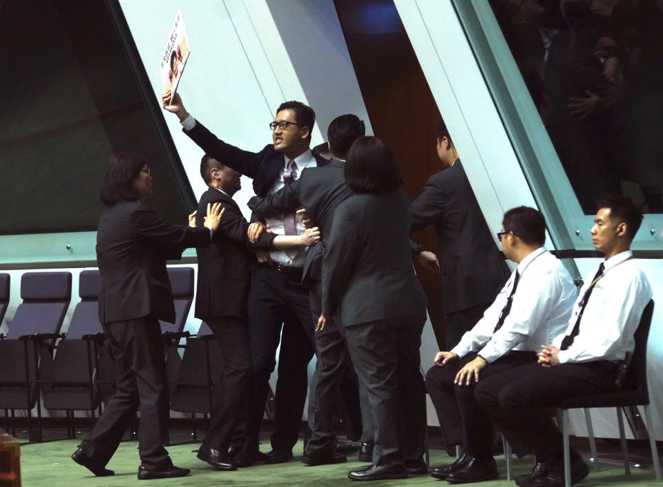 Pro-democracy lawmaker Gray Fa, center, is forcibly removed from the chamber of the Legislative Council for interrupting Hong Kong Chief Executive Carrie Lam attending a question and answer session in Hong Kong, Thursday, Oct. 17, 2019. (AP Photo/Vincent Yu)