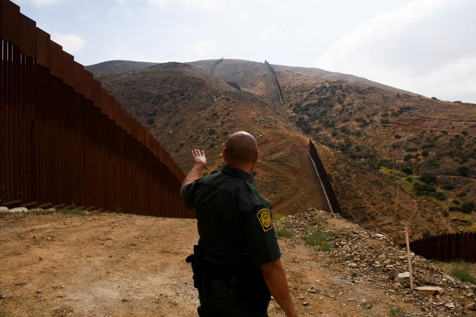 A U.S. Border Patrol agent shows an incomplete section of the new steel bollard-style border wall on a hillside along the U.S.-Mexico border between San Diego and Tijuana in May 2021. 