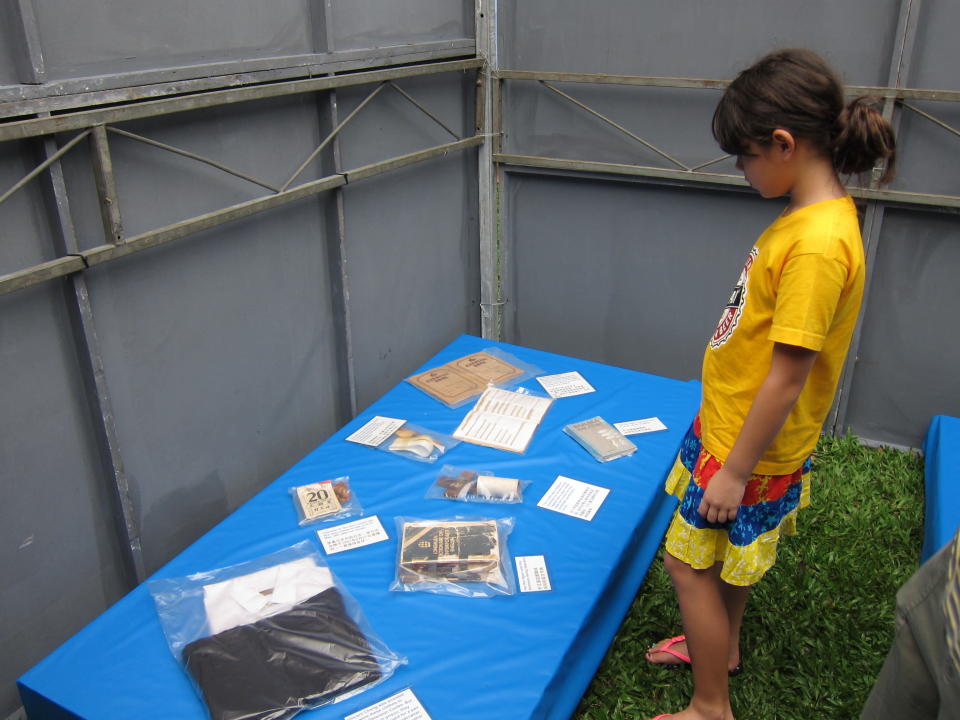 A girl looks at the items laid out in the exhibit of a two-bed cell.