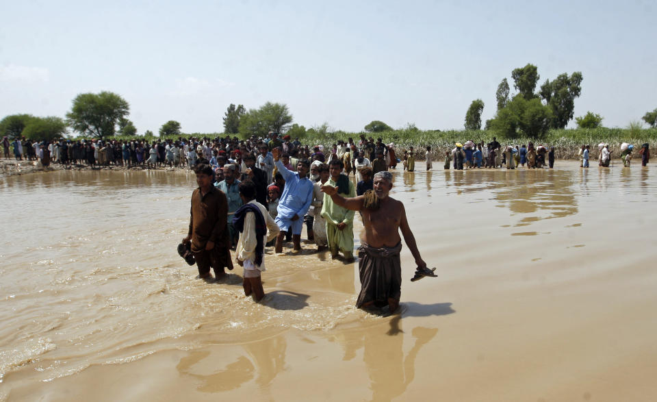 Victims of unprecedented flooding from monsoon rains line up to receive relief aid organized by the Edhi Foundation, in the Ghotki District of Sindh Pakistan, Wednesday, Sept. 7, 2022. (AP Photo/Fareed Khan)