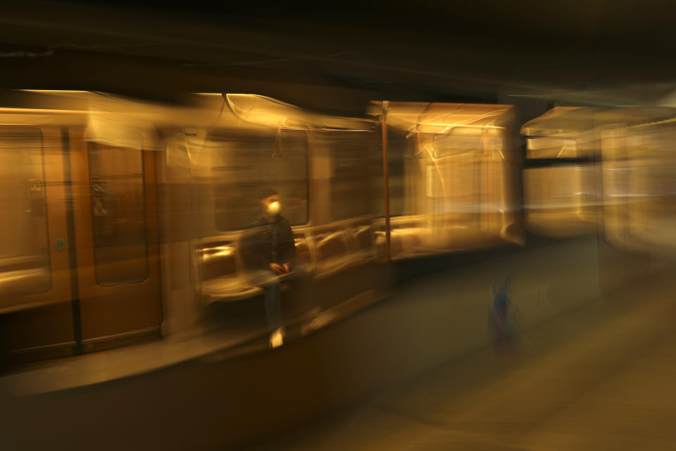 FILE - A man wearing a face masks travels in a virtually empty metro in Brussels, Thursday, March 19, 2020, during lockdown measures following in the steps of European neighbours Italy, Spain and France. For most people, the new coronavirus causes only mild or moderate symptoms, such as fever and cough. For some, especially older adults and people with existing health problems, it can cause more severe illness, including pneumonia. (AP Photo/Francisco Seco, File)