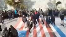 Social media video still shows several people walking on U.S. and Israeli flags while others avoid stepping on the flags by walking around them, at the Shahid Beheshti University in Tehran