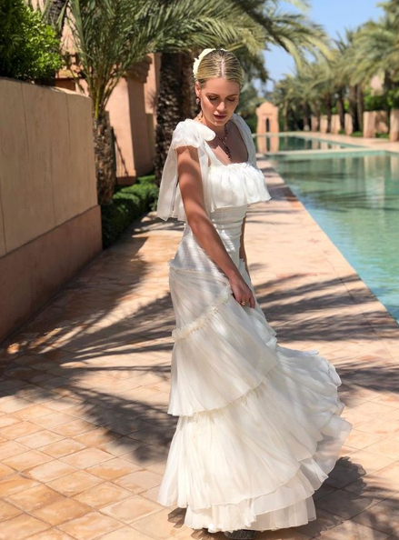 Lady Kitty Spencer wearing a flowing white gown beside a swimming pool.