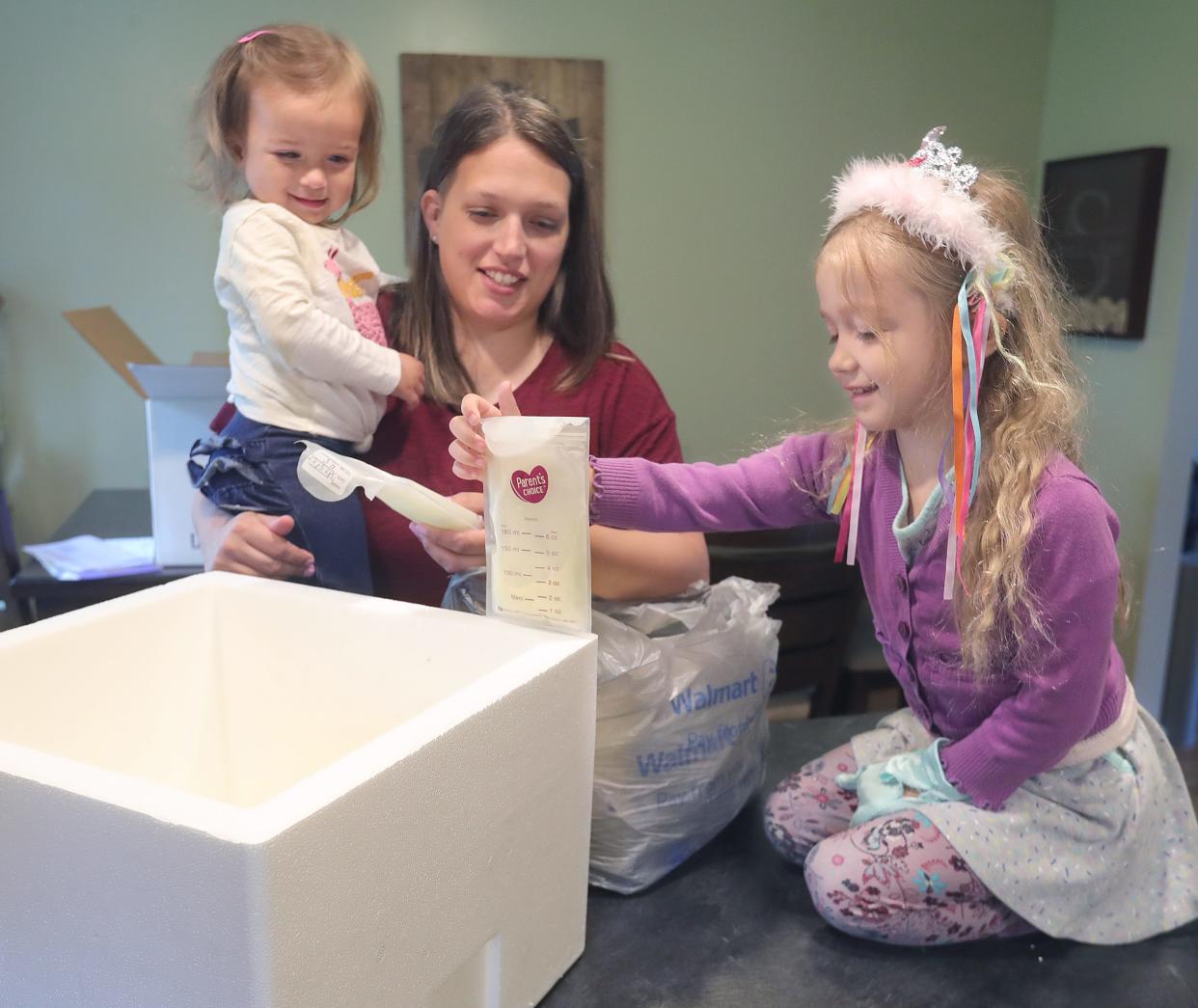 Maddie Sponsler gets help from daughters Katelynn, 20 months, and Julia, 4, with packing bags of breast milk to send to OhioHealth Mothers' Milk Bank on Monday in Wadsworth.