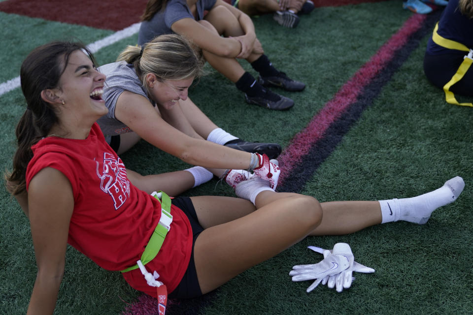 Olivia D'Angelo, 16, rubs the foot of Raychel Watts, 16, front, as they and other Redondo Union High School girls try out for a flag football team on Thursday, Sept. 1, 2022, in Redondo Beach, Calif. Southern California high school sports officials will meet on Thursday, Sept. 29, to consider making girls flag football an official high school sport. This comes amid growth in the sport at the collegiate level and a push by the NFL to increase interest. (AP Photo/Ashley Landis)