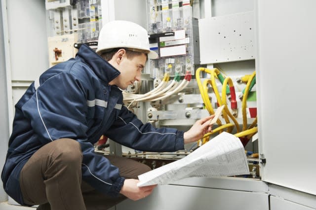 Electrician builder at work inspecting cabling connection of high voltage power electric line in industrial distribution fuseboa