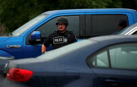 A Dallas police officer stands between parked cars in front of the Dallas Police Department headquarters after an anonymous threat was reported in Dallas, Texas, U.S. July 9, 2016. REUTERS/Carlo Allegri