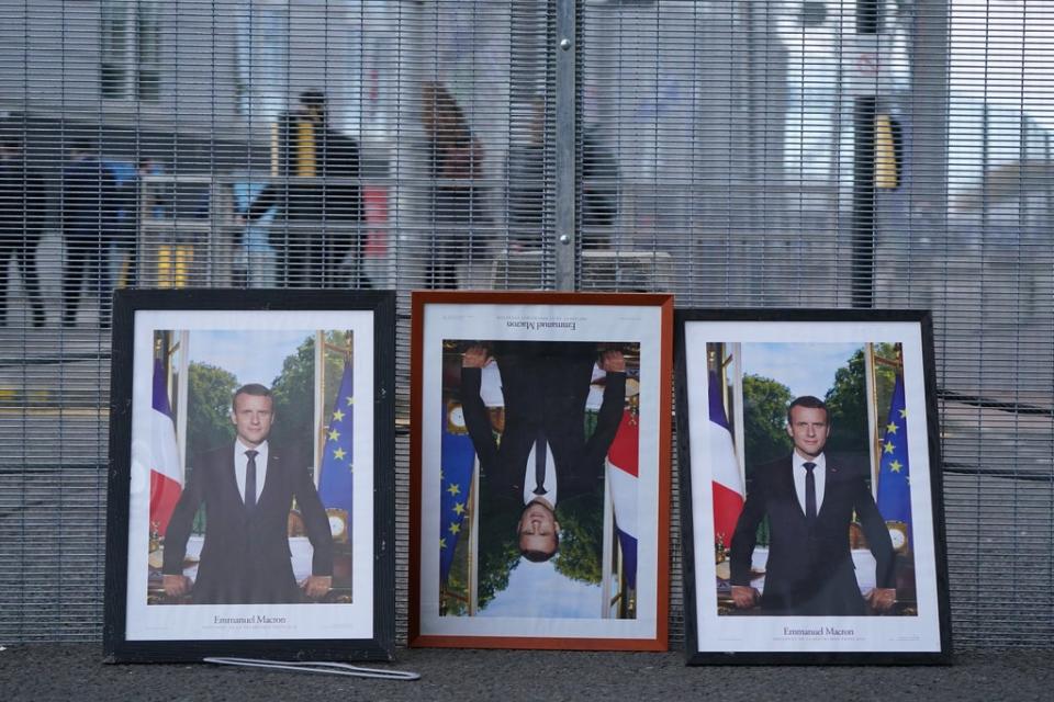 Three framed photographs of French President Emmanuel Macron propped up along the fencing on the perimeter of the Cop26 summit in Glasgow (Andrew Milligan/PA) (PA Wire)