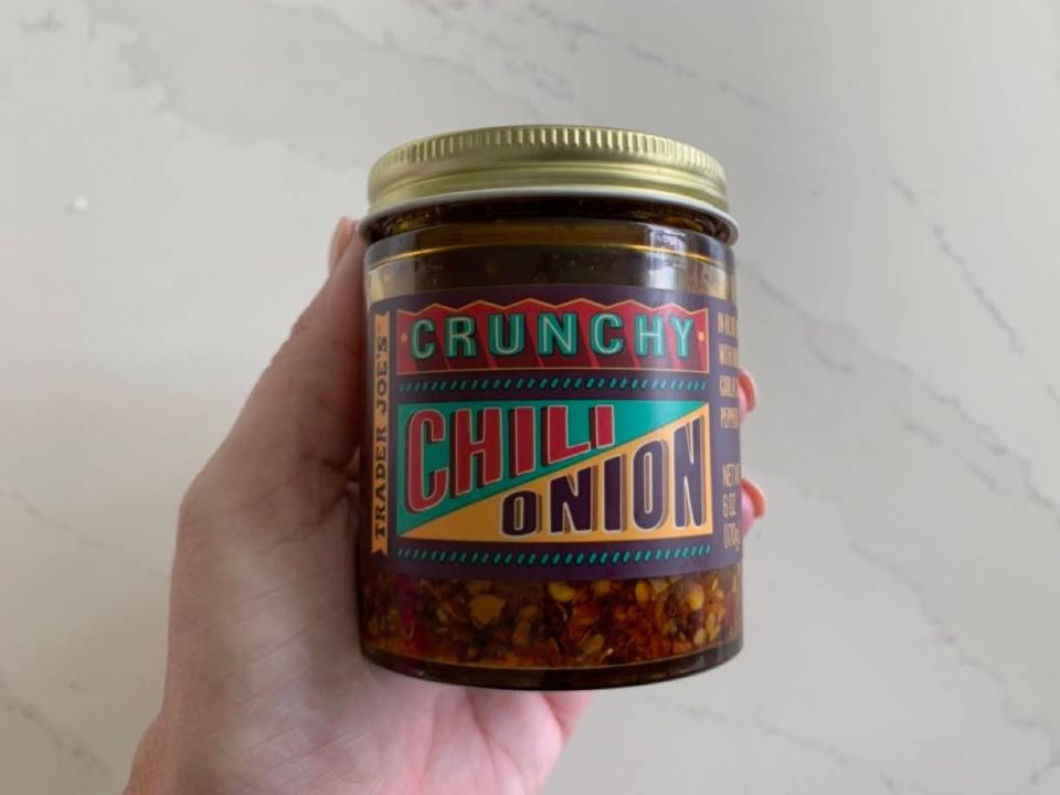 A jar of Trader Joe's crunchy chili-onion oil on a marble countertop.