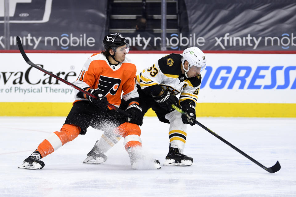 Boston Bruins' Brad Marchand, right, and Philadelphia Flyers' Travis Konecny chase the puck during the third period of an NHL hockey game, Tuesday, April 6, 2021, in Philadelphia. The Bruins won 4-2. (AP Photo/Derik Hamilton)