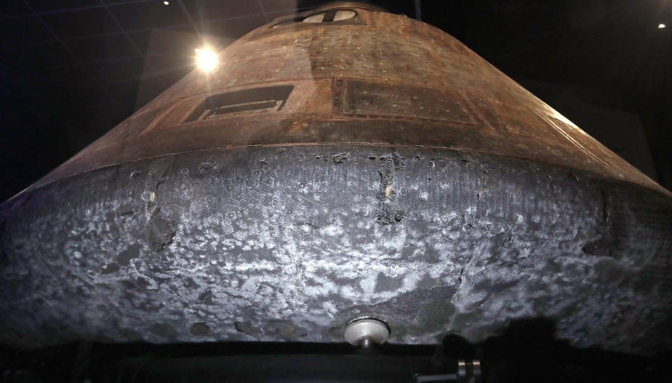FILE - This April 11, 2019 file photo shows NASA's Apollo 11 command module Columbia, its bottom scorched and pitted from reentry into Earth's atmosphere decades earlier, as the centerpiece of Destination Moon: The Apollo 11 Mission exhibit at the Museum of Flight in Seattle. The exhibit celebrates the 50th anniversary of the U.S. manned moon landing on July 20, 1969. (AP Photo/Elaine Thompson)