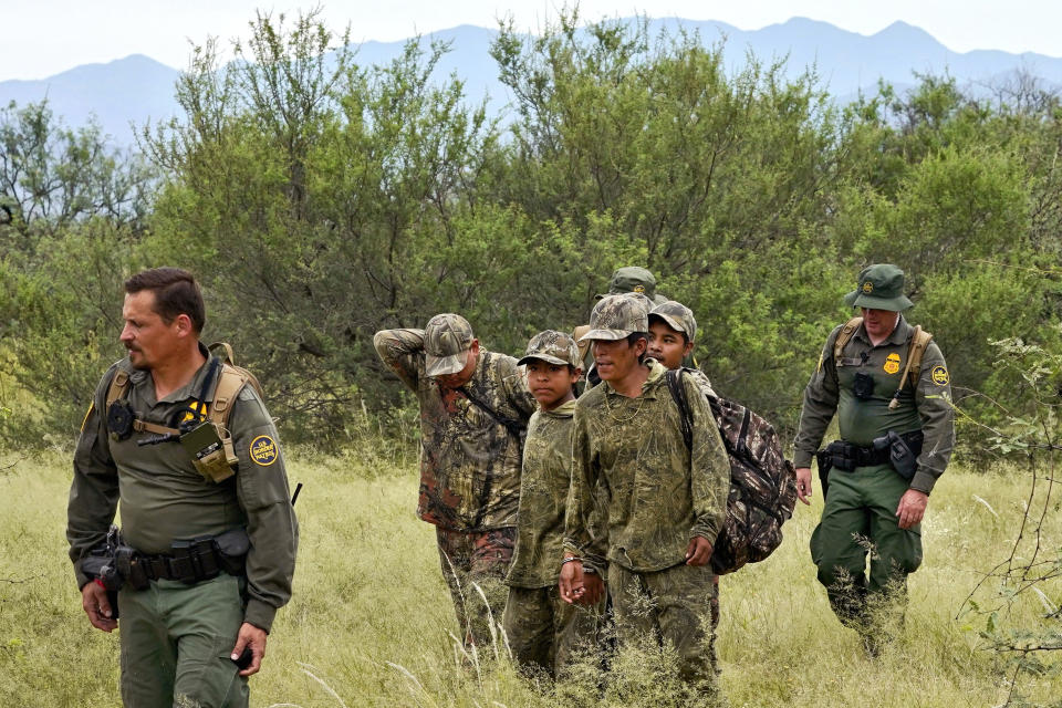 Migrants are led through desert at the base of the Baboquivari Mountains after being apprehended by U.S. Border Patrol agents, Thursday, Sept. 8, 2022, near Sasabe, Ariz. by U.S. Border Patrol agents. The desert region located in the Tucson sector just north of Mexico is one of the deadliest stretches along the international border with rugged desert mountains, uneven topography, washes and triple-digit temperatures in the summer months. Border Patrol agents performed 3,000 rescues in the sector in the past 12 months. (AP Photo/Matt York)