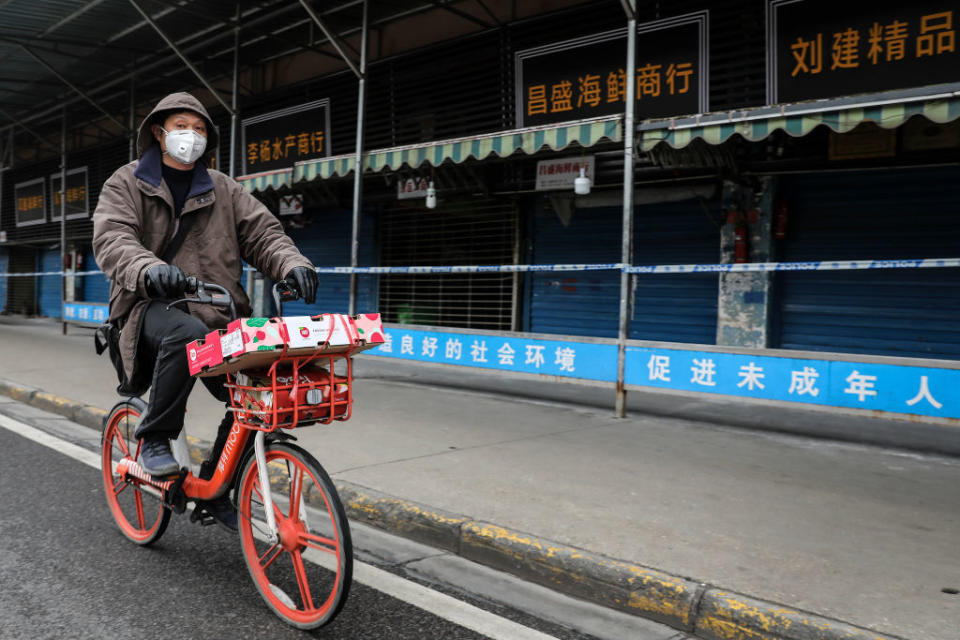 A man wears a mask while riding a bike past the closed Huanan Seafood Wholesale Market, which has been linked to the coronavirus in Wuhan, Hubei province, China on Jan. 17, 2020. | Getty Images