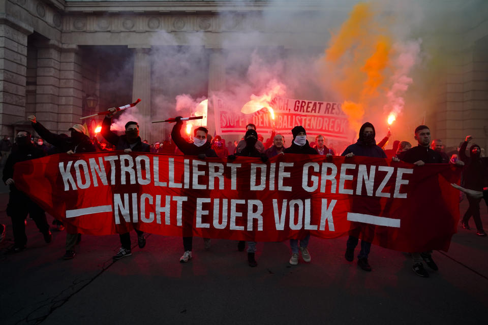 Demonstrators shout slogans and light flares during a demonstration against measures to battle the coronavirus pandemic in Vienna, Austria, Saturday, Nov. 20, 2021. Thousands of protesters are expected to gather in Vienna after the Austrian government announced a nationwide lockdown to contain the quickly rising coronavirus infections in the country. Banner reads: ' Controls the border. Not your people'. (AP Photo/Florian Schroetter)