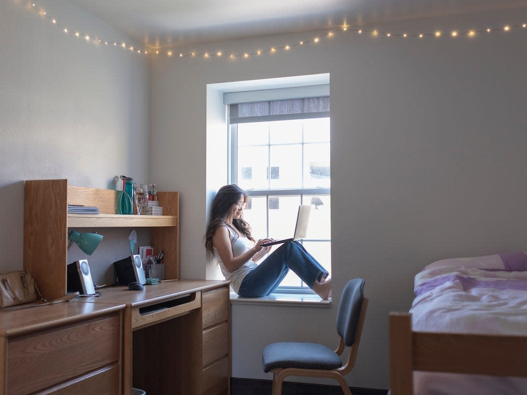 Young woman college student in her dorm room with laptop `