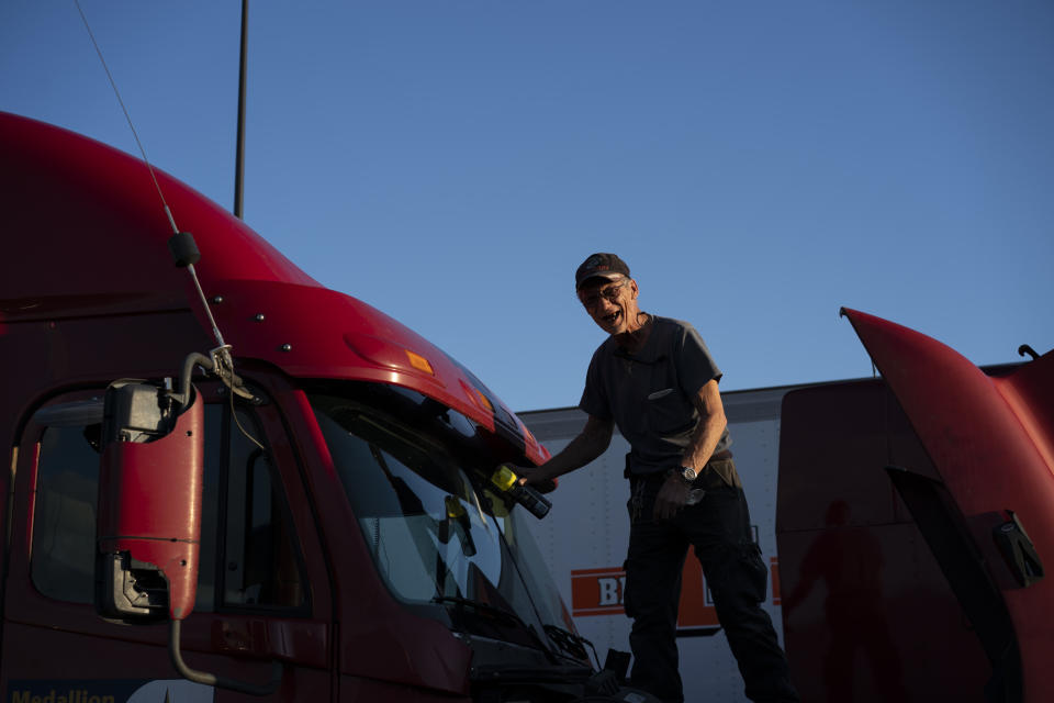 In this April 6, 2020, photo, truck driver Mark Serafin from Georgia, washes the windshield of his semitruck on the lot of Love's Travel Stop truck stop in Greenville, Va. Serafin is traveling back home from Greenville because the profits have become erratic during the coronavirus outbreak. (AP Photo/Carolyn Kaster)