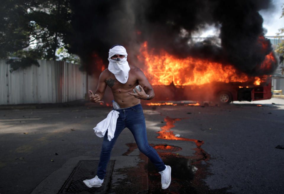 An opposition demonstrator gestures in front of a burning bus, while holding a rock, near the Generalisimo Francisco de Miranda Airbase "La Carlota" in Caracas, Venezuela April 30, 2019. (Photo: Ueslei Marcelino/Reuters)