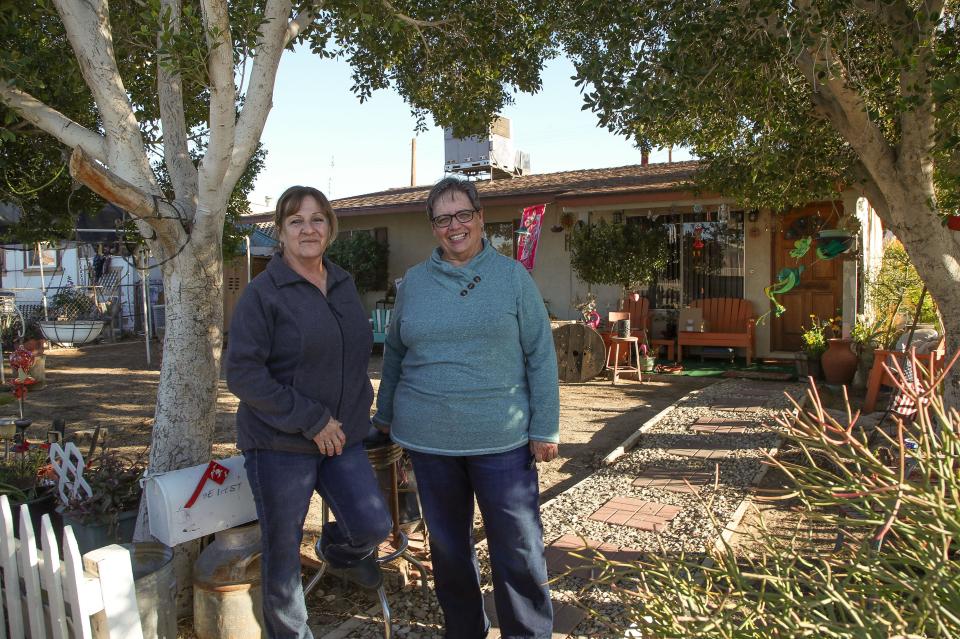 Sisters Gloria Saiza and Diana Juarez stand outside their family home in Niland, Calif. on March 2, 2023. Juarez says her monthly water bills near $200 during summer months. She waters a little bit to keep Indian laurels her mother planted alive, but the rest of the yard is bare dirt, and she cannot afford to buy and fill a kiddie pool for her grandchildren due to high rates charged by private Golden State Water Co.