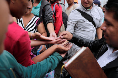 A pastor gives money to Honduran migrants, part of a caravan trying to reach the U.S., outside a migrant shelter in Guatemala City, Guatemala October 17, 2018. REUTERS/Luis Echeverria