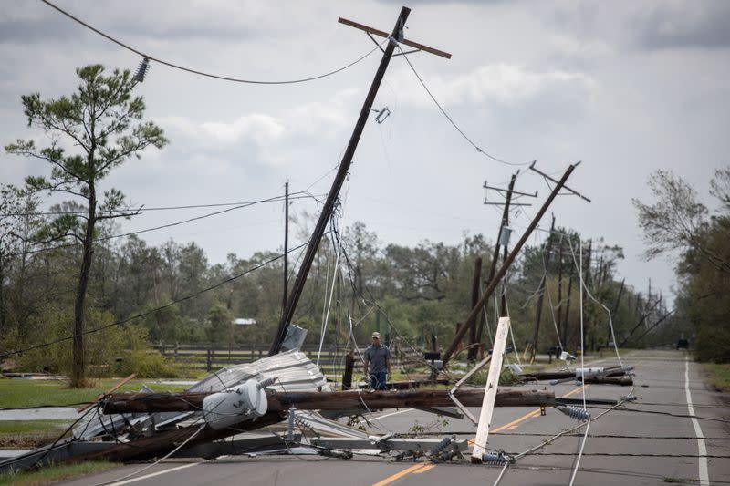 Man walks past fallen electrical lines to get to residence in aftermath of Hurricane Laura in Sulphur, Louisiana