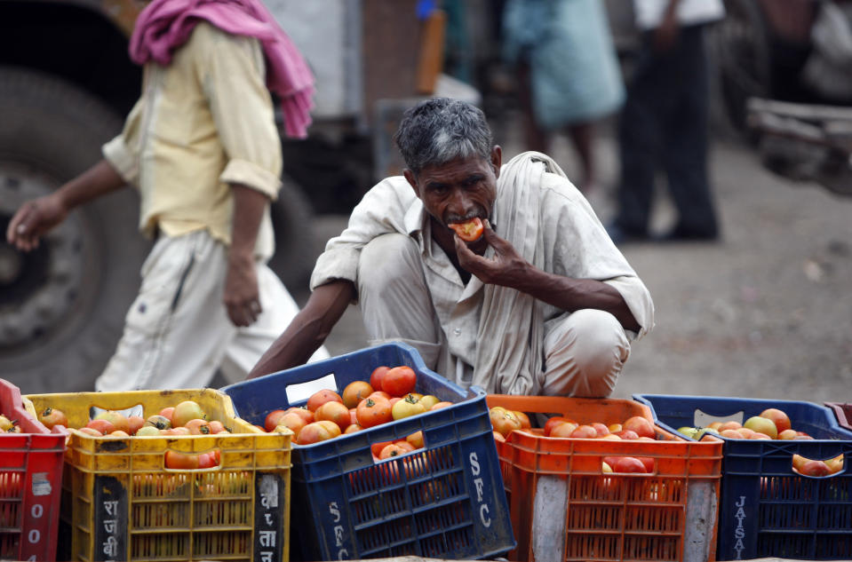 In this Aug. 3, 2011, file photo, a laborer eats a tomato at one of Asia's biggest wholesale markets, Azadpur mandi, in New Delhi, India. United Nations agencies are warning that more than 350 million people in the Asia-Pacific are going hungry as the coronavirus pandemic destroys jobs and pushes food prices higher. (AP Photo/Mustafa Quraishi, File)