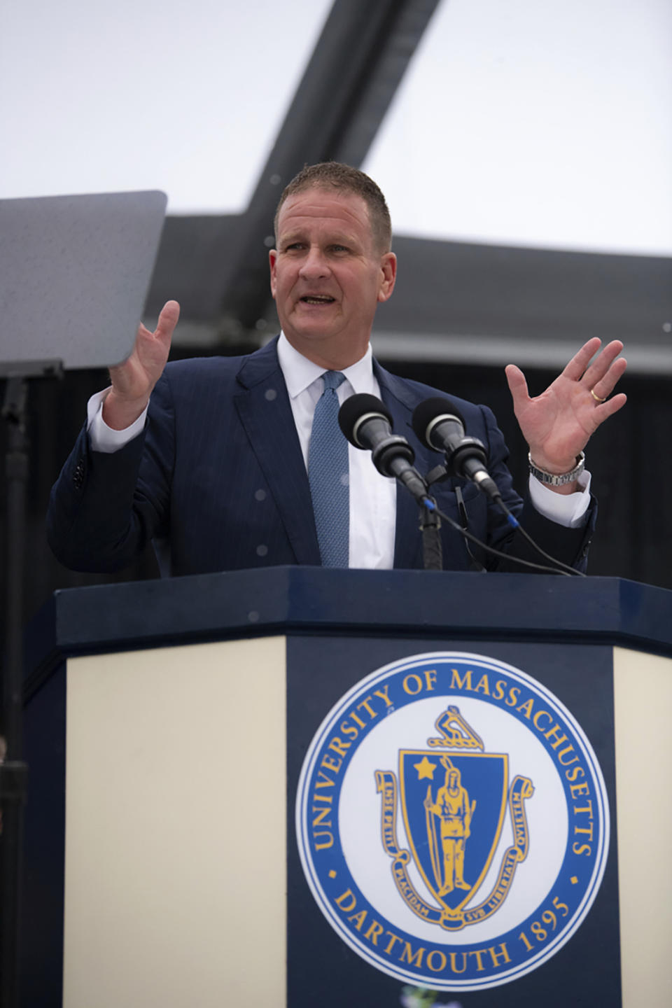 In this photo provided by University of Massachusetts Dartmouth, billionaire Robert Hale speaks onstage at the graduation ceremony Thursday, May 16, 2024, in Dartmouth, Mass. Hale gifted graduates at the University of Massachusetts Dartmouth each with $1,000., with the condition that they give $500 away. Hale revealed the gift to more than 1,100 graduates. (Karl Christoff Dominey/University of Massachusetts Dartmouth via AP)