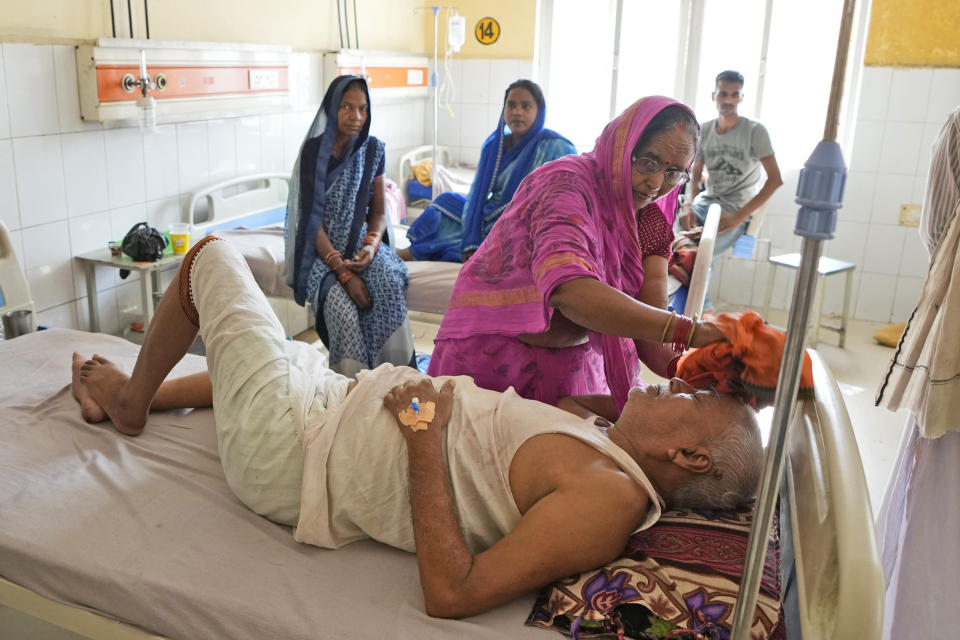 Shiela Mishra wipes the head of her ailing brother to keep him cool from the heat wave by using a wet cloth at the district hospital in Ballia, Uttar Pradesh state, India, Monday, June 19, 2023. Several people have died in two of India's most populous states in recent days amid a searing heat wave, as hospitals find themselves overwhelmed with patients. More than hundred people in the Uttar Pradesh state, and dozens in neighboring Bihar state have died due to heat-related illness. (AP Photo/Rajesh Kumar Singh)