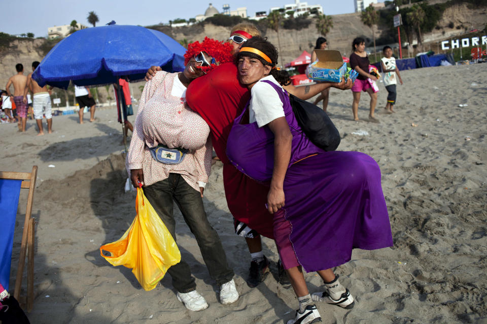 In this Jan. 17, 2013 photo, performers who also sell candies pose for a photo on Agua Dulce beach in Lima, Peru. While Lima's elite spends its summer weekends in gate beach enclaves south of the Peruvian capital, the working class jams by the thousands on a single municipal beach of grayish-brown sands and gentle waves. The only barrier to entry to Agua Dulce beach is two dollars, the price of bus fare to get there and home. (AP Photo/Rodrigo Abd)