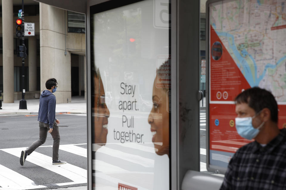 A man uses a crosswalk as he wears a face mask to protect against the spread of the new coronavirus, Thursday, May 21, 2020, in Washington. The District of Columbia is under a stay-home order for all residents in an effort to slow the spread of the new coronavirus. (AP Photo/Patrick Semansky)