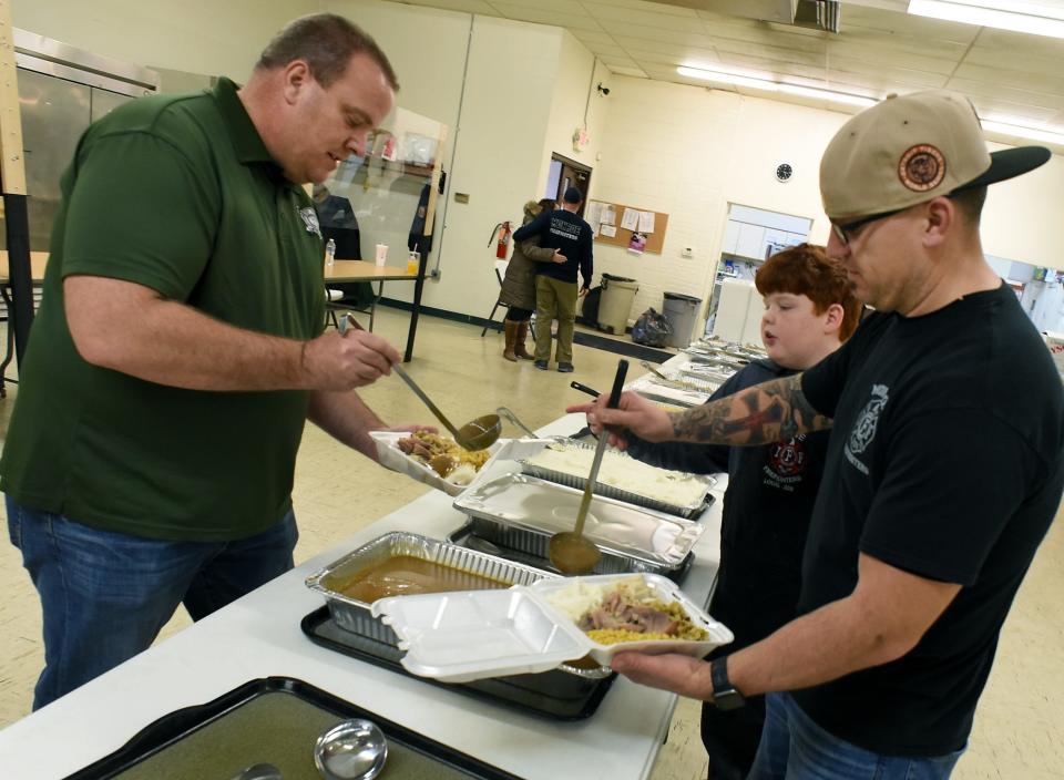 City of Monroe Fire Chief Rob Wight, firefighter Daryll Yarger and Nicholas Hudson, son of firefighter Chad Hudson, start plate the Thanksgiving meals which were given out to folks outside at Oaks Village in Monroe Wednesday, November 24, 2021.