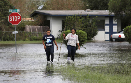 Residents walk through flood waters left in the wake of Hurricane Irma in a suburb of Orlando, Florida, U.S., September 11, 2017. REUTERS/Gregg Newton