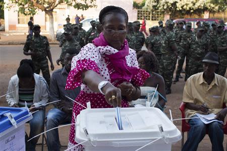 A woman casts her ballot at a polling station as soldiers watch in Bissau, April 13, 2014. REUTERS/Joe Penney