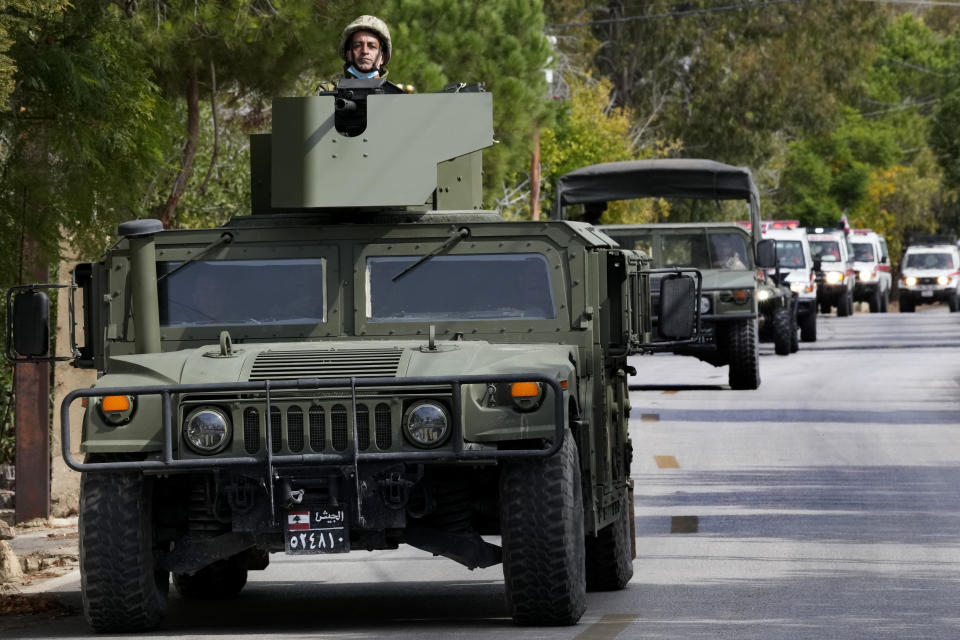 FILE - Lebanese army armoured vehicles lead a convoy of the Lebanese Red Cross ambulances that carry dead bodies of Hezbollah fighters who were killed on Tuesday during a clash with Israeli army, in Alma al-Shaab, a Lebanese border village with Israel, south Lebanon, Wednesday, Oct. 18, 2023. A war of words that has unfolded in Lebanon show longstanding schisms in the small country over Hezbollah, now amplified by the militant group's role in the Lebanon-Israel border clashes and by fears that an already crisis-hit Lebanon could be dragged into an all-out war. (AP Photo/Hussein Malla, File)