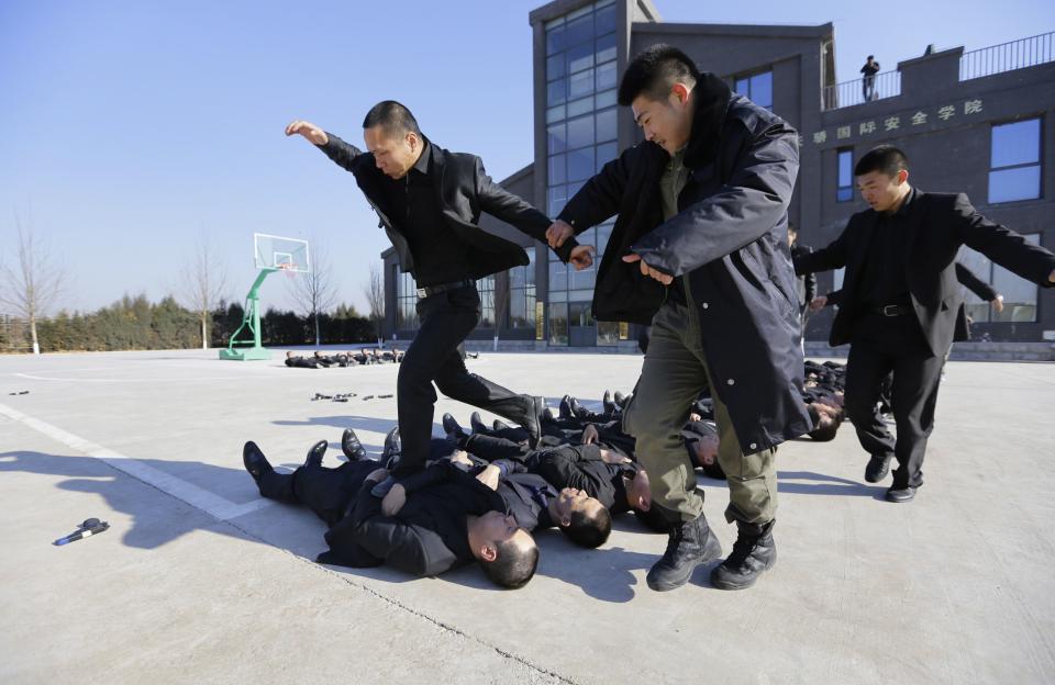 Students run over the bodies of fellow trainees at the Tianjiao Special Guard/Security Consultant training camp on the outskirts of Beijing December 11, 2013. Former Chinese soldier Chen Yongqing has big ambitions for his bodyguard training school Tianjiao, which he says is China's first professional academy to train former soldiers and others as personal security guards. Chen charges 500,000 yuan ($82,400) a year for each protector as China's rich and famous look to bolster their safety and sense of importance. Picture taken December 11, 2013. REUTERS/Jason Lee (CHINA - Tags: BUSINESS SOCIETY) ATTENTION EDITORS: PICTURE 04 OF 26 FOR PACKAGE 'CHINA'S BODYGUARD SCHOOL' TO FIND ALL IMAGES SEARCH 'TIANJIAO'