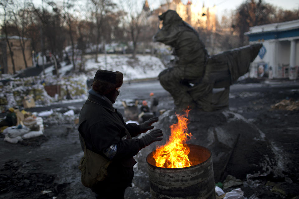An opposition supporter warms himself next to a bonfire as he guards one of the barricades heading to Kiev's Independence Square, the epicenter of the country's current unrest, Ukraine, Monday, Feb. 3, 2014. Ukraine's president will return Monday from a short sick leave that had sparked a guessing game he was taking himself out of action in preparation to step down or for a crackdown on widespread anti-government protests. (AP Photo/Emilio Morenatti)