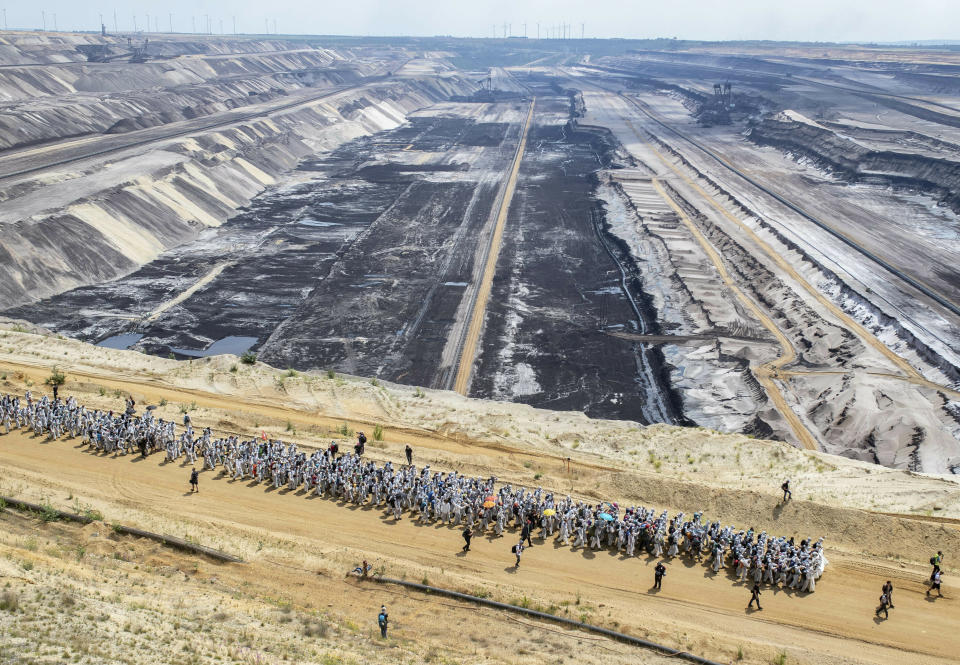 Numerous environmental activists walk on a roadway on the site of the Garzweiler open-cast mine in Garzweiler, Germany, Saturday, June 22, 2019. The protests for more climate protection in the Rhineland continue. (Marcel Kusch/dpa via AP)