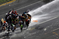 <p>Demonstrators are hit by a jet of water during clashes at a march to the state ombudsman’s office in Caracas, Venezuela, May 29, 2017. (Carlos Garcia Rawlins/Reuters) </p>