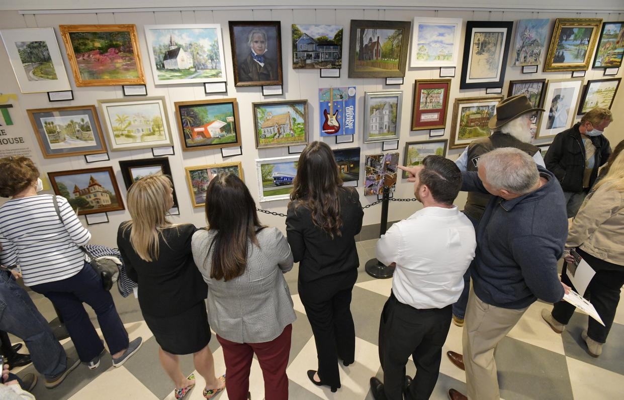 Visitors look over the artwork on display at the opening of the first Clay County Art in the Courthouse program in Green Cove Springs. The Wednesday premiere opened with 33 paintings assembled by the Art Guild of Orange Park.