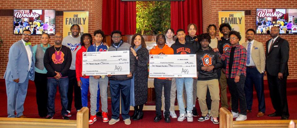 Several members of the Millwood and Douglass high school boys basketball teams, along with adult supporters, pose for a picture with Gary Jones Jr., far left at Eastside Church of Christ, after Jones' announced the church's monetary donations to help purchase the teams' state championship rings.