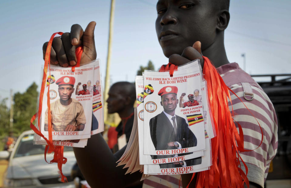 A supporter holds posters of pop star-turned-opposition lawmaker Bobi Wine, whose real name is Kyagulanyi Ssentamu, at his home in Kampala, Uganda Thursday, Sept. 20, 2018. Wine vowed Thursday to continue his fight for more freedom in the country "or we shall die trying," shortly after security forces took him into custody on his arrival from the United States after treatment for alleged torture. (AP Photo/Ronald Kabuubi)