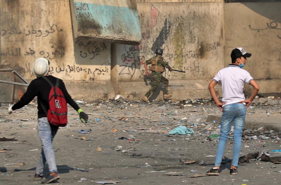 A soldier runs for cover while anti-government protesters throw stones and Molotov cocktails during clashes on Rasheed Street, Baghdad, Iraq, Tuesday, Nov. 26, 2019. (AP Photo/Khalid Mohammed)