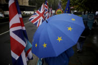 An anti-Brexit remain in the European Union supporter protests with a European flag design umbrella opposite the Houses of Parliament in London, Thursday, Oct. 24, 2019. Britain's Prime Minister Boris Johnson won Parliament's backing for his exit deal on Wednesday, but then lost a key vote on its timing, effectively guaranteeing that Brexit won't happen on the scheduled date of Oct. 31. (AP Photo/Matt Dunham)